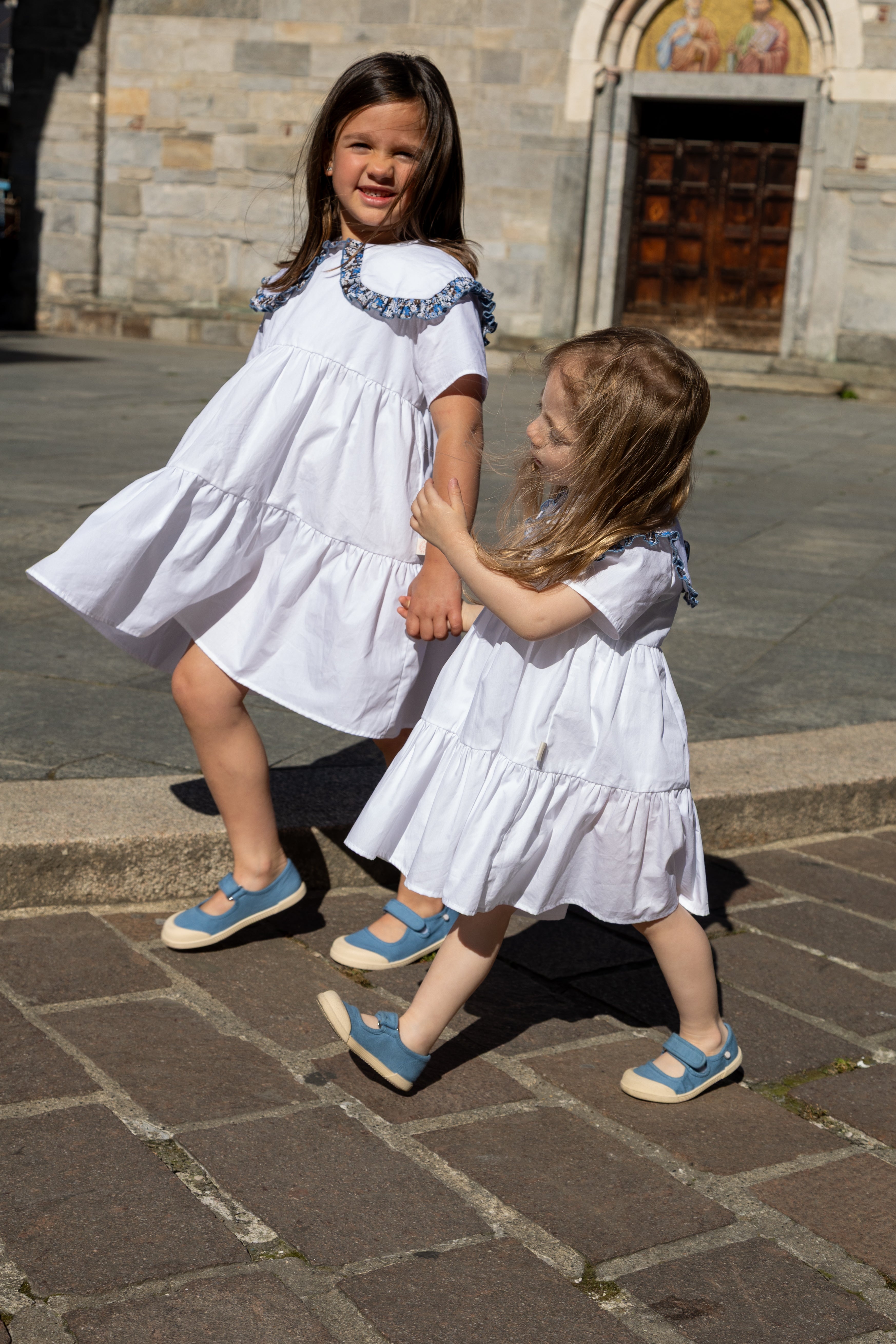 Bambina cammina per strada indossando l'abito bianco Meringa di Amtea